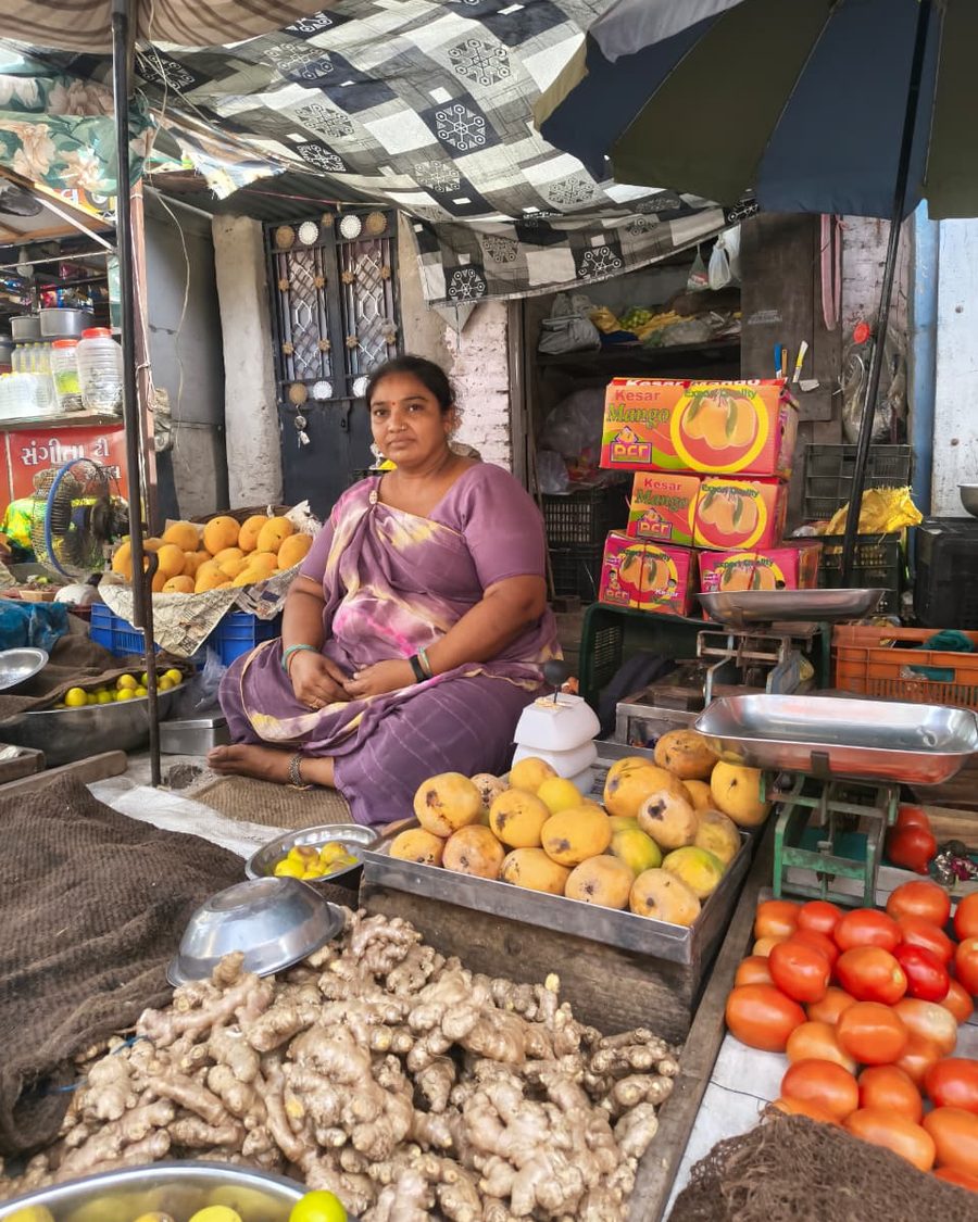 A SEWA member at her market stall in India, surrounded by produce.